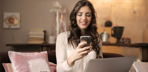 Mujer joven accediendo a internet desde un móvil y laptop